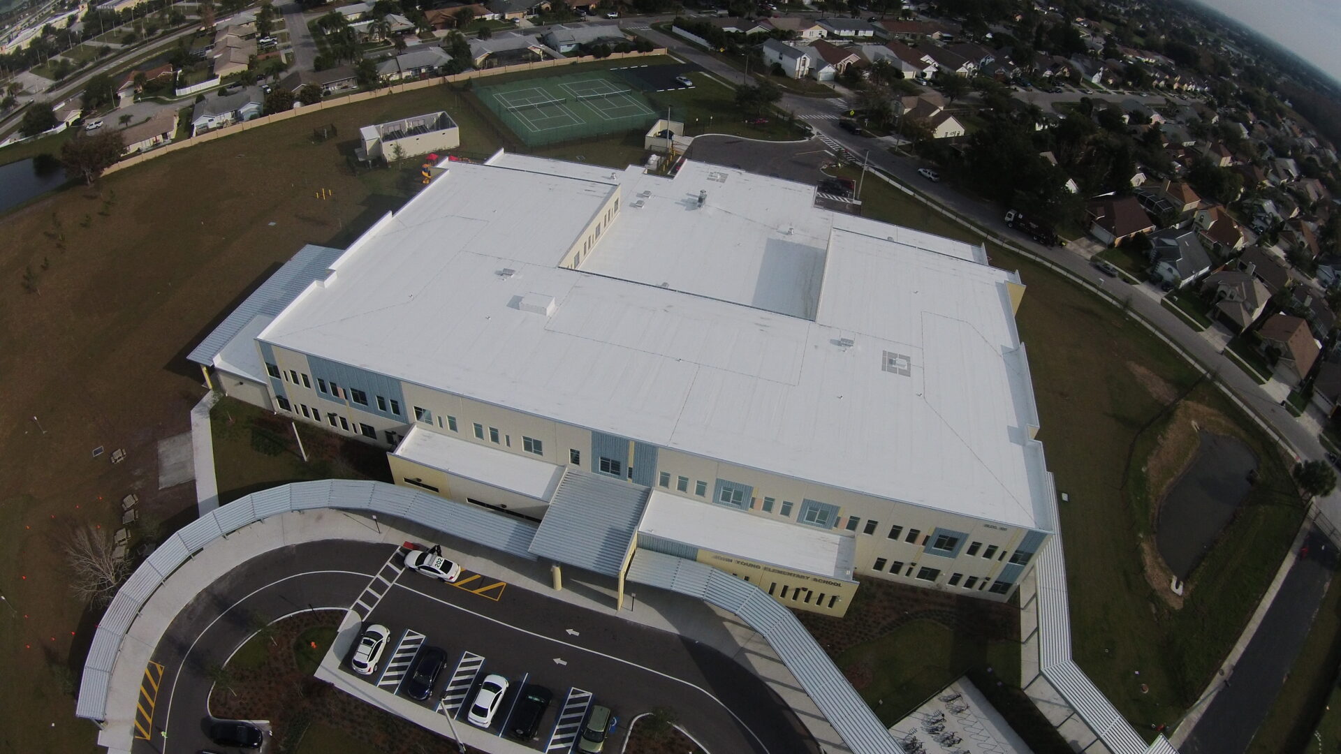 An aerial view of a school building with a white roof, showcasing past projects.