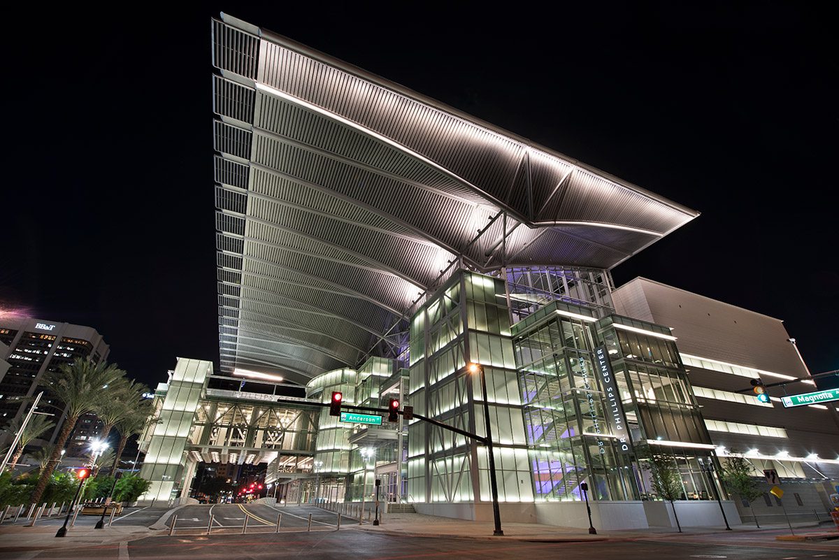 A glass-roofed building illuminated at night, showcasing the architectural excellence of our past projects.